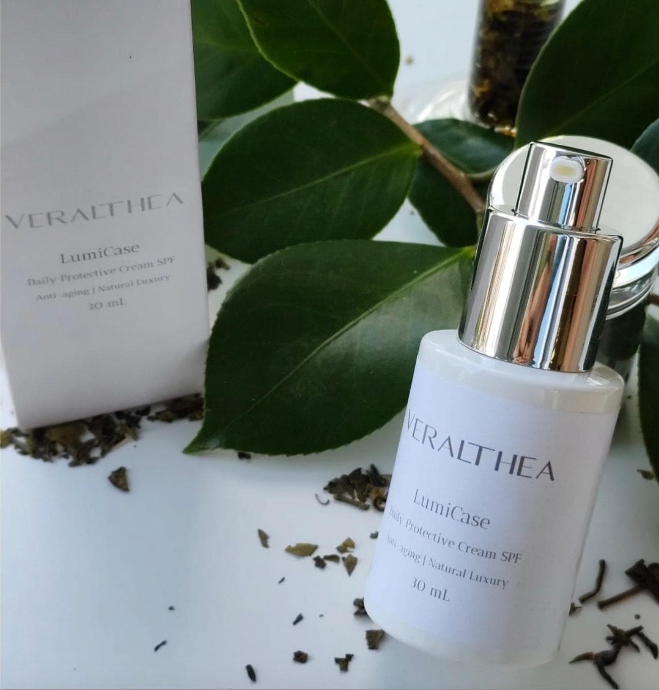 Frasco de creme protetor Veralthea LumiCase com caixa branca, folhas verdes e ervas secas.